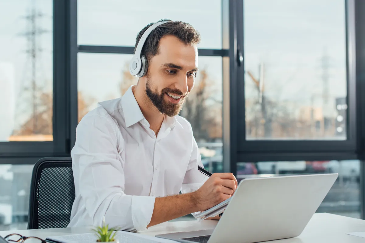 Werde Industriekaufmann/-frau und setze Deine planerischen Fähigkeiten bei uns ein. Foto eines jungen Mannes, der ein Headset trägt und an einem Notebook arbeitet.